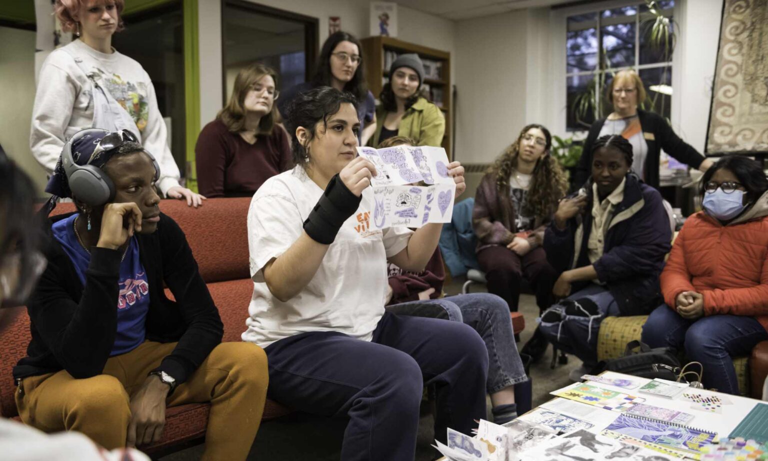 Art New York participant Angelica Aranda holds up a sheet of paper with art on it during a zine-making workshop.