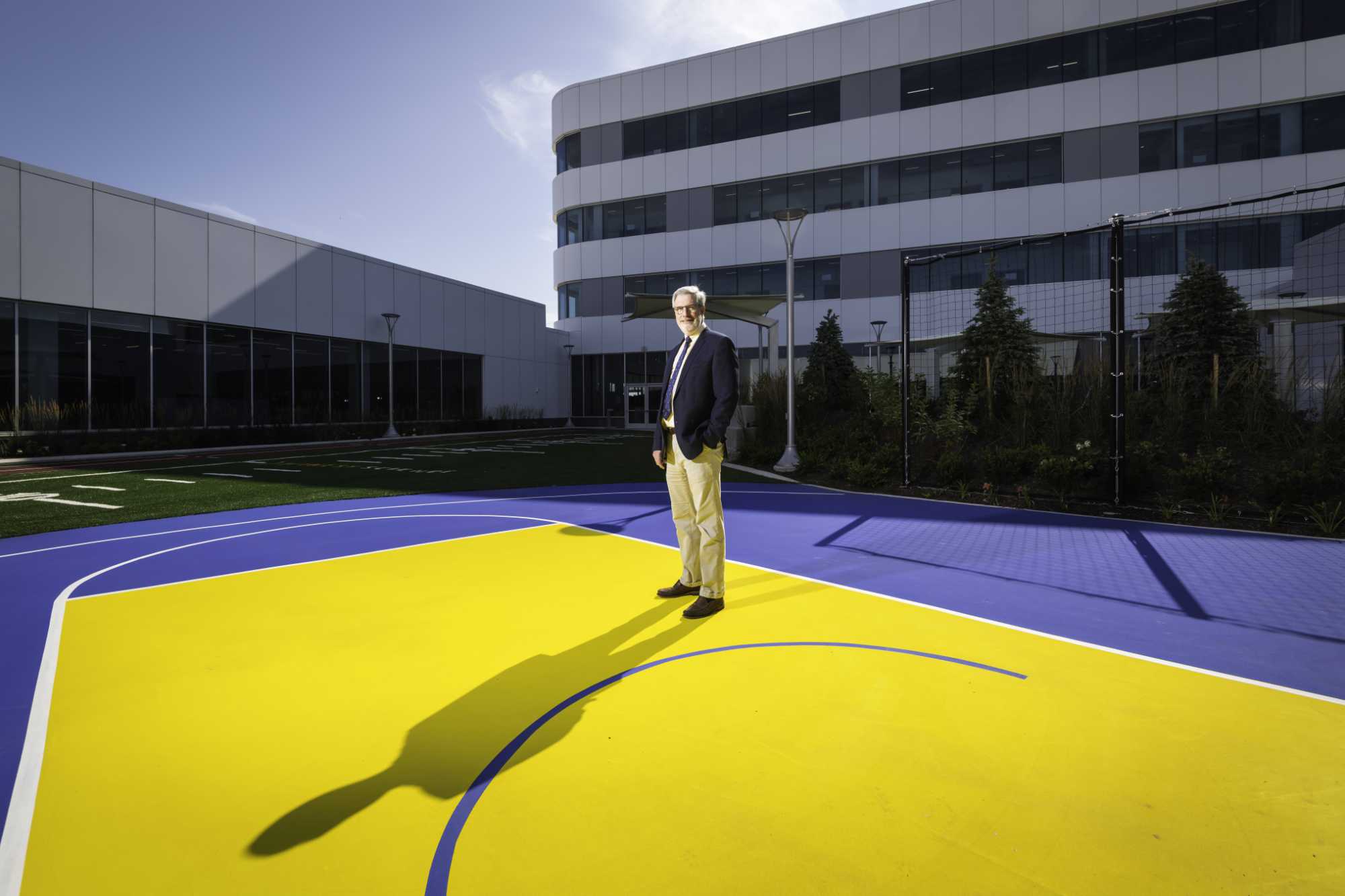 Paul Rubery in the outdoor courtyard of the new orthopeadic center featuring a small football field and a blue-and-yellow basketball court.