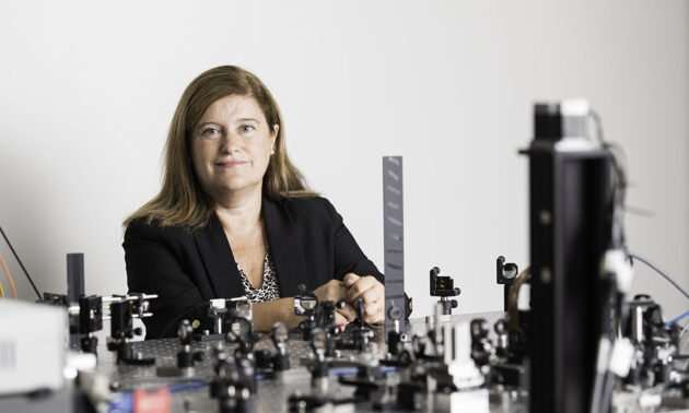 Susana Marcos rests her arms on a bench in her lab filled with optical instruments.