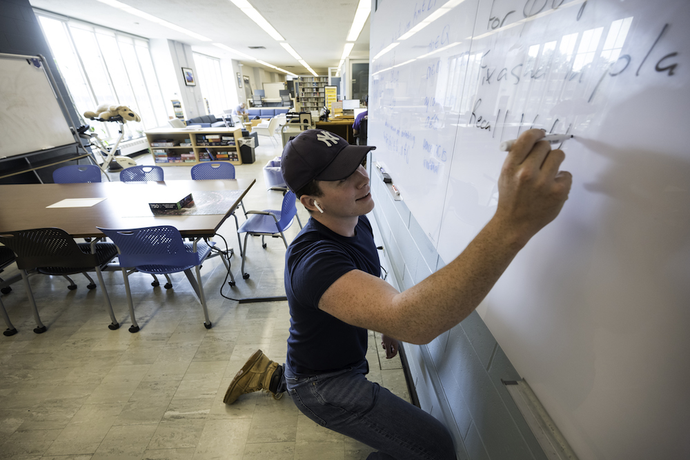 Student writes on white board at Renovated Physics-Optics-Astronomy Library