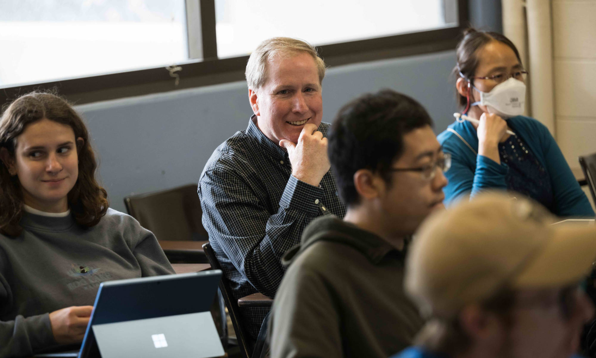 Feature image James McGrath sits among his biomedical engineering students in a Hylan Hall classroom.