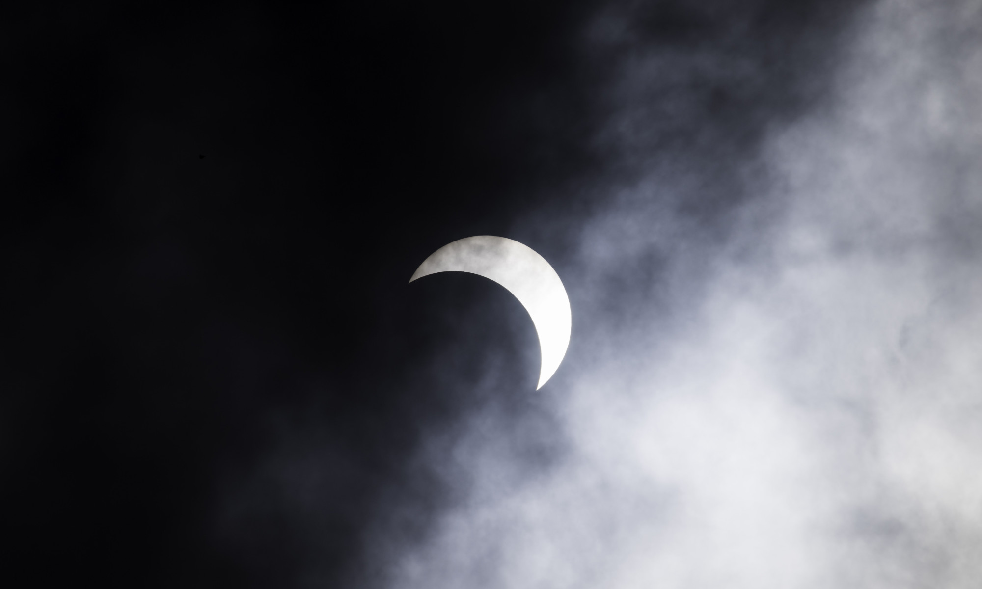 Partial solar eclipse seen through clouds.