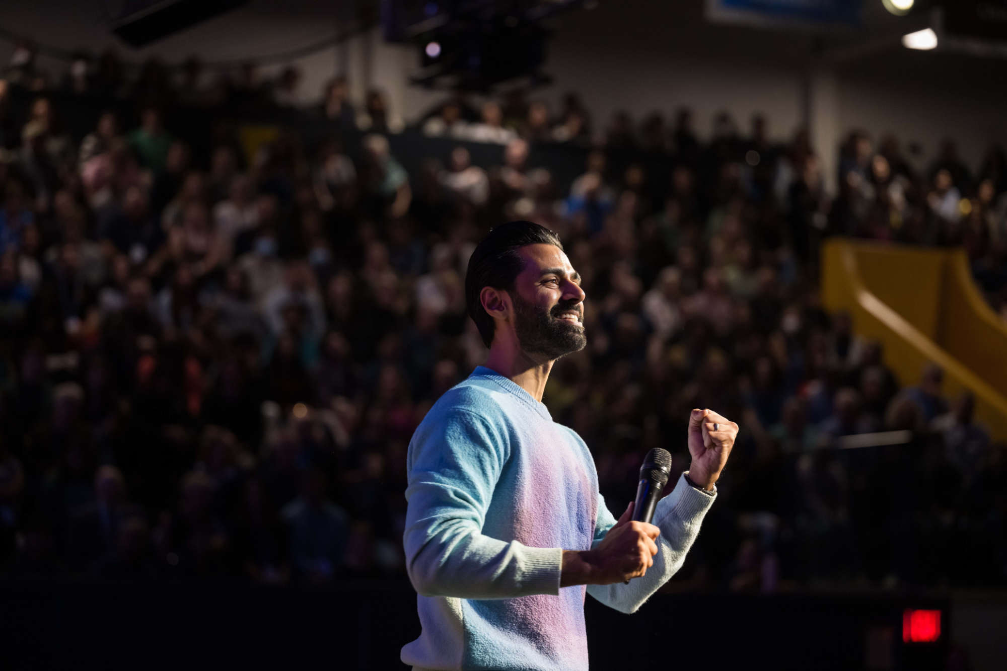 Hasan Minhaj pumps his fist on the Palestra stage at Meliora Weekend 2023.