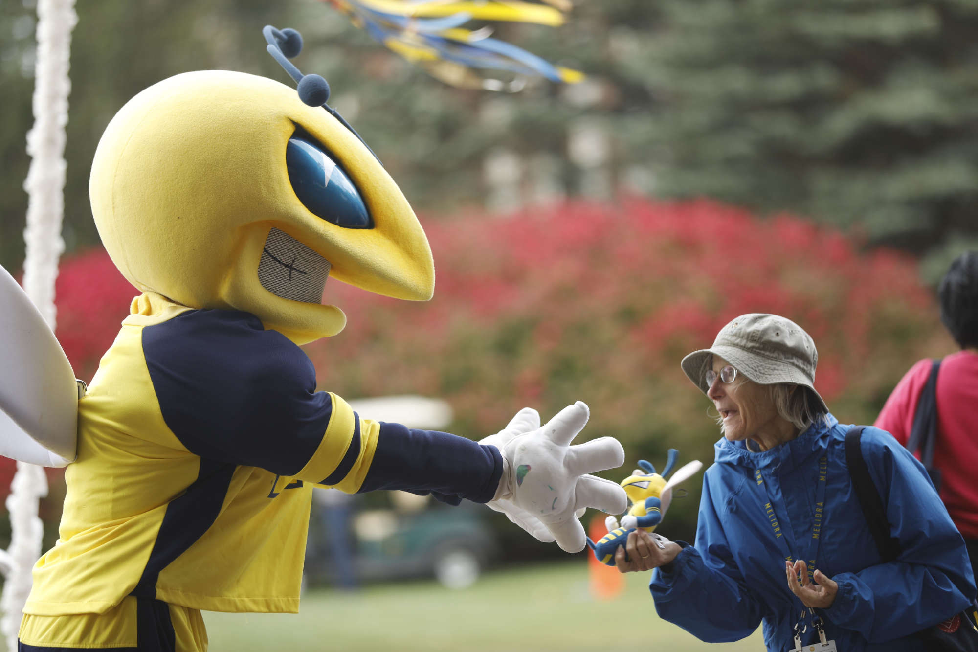 University of Rochester mascot Rocky reaches toward a stuffed version of him held by a guest at Meliora Weekend 2023.