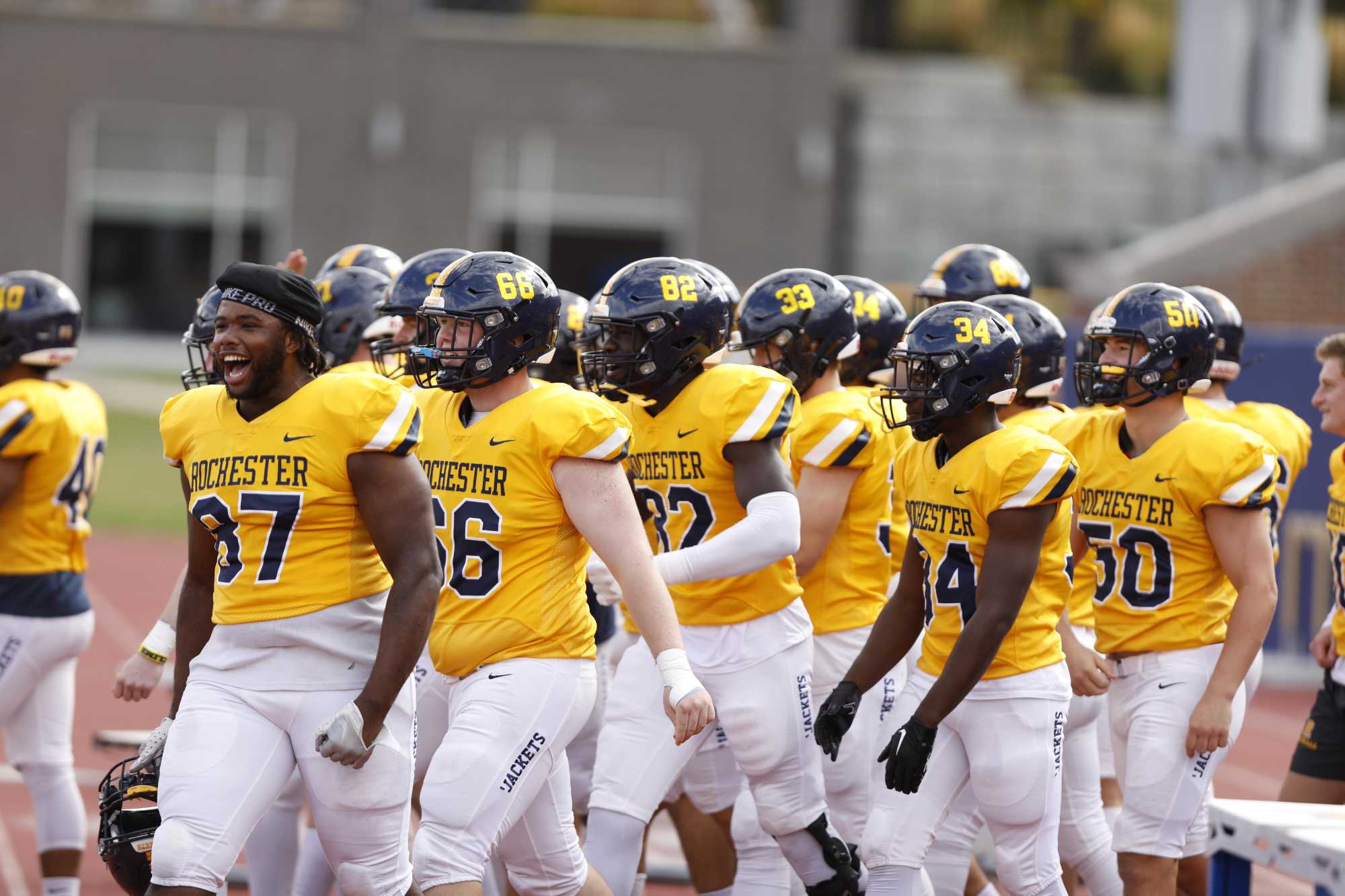 University of Rochester Yellowjackets football players in uniform heading toward the field.