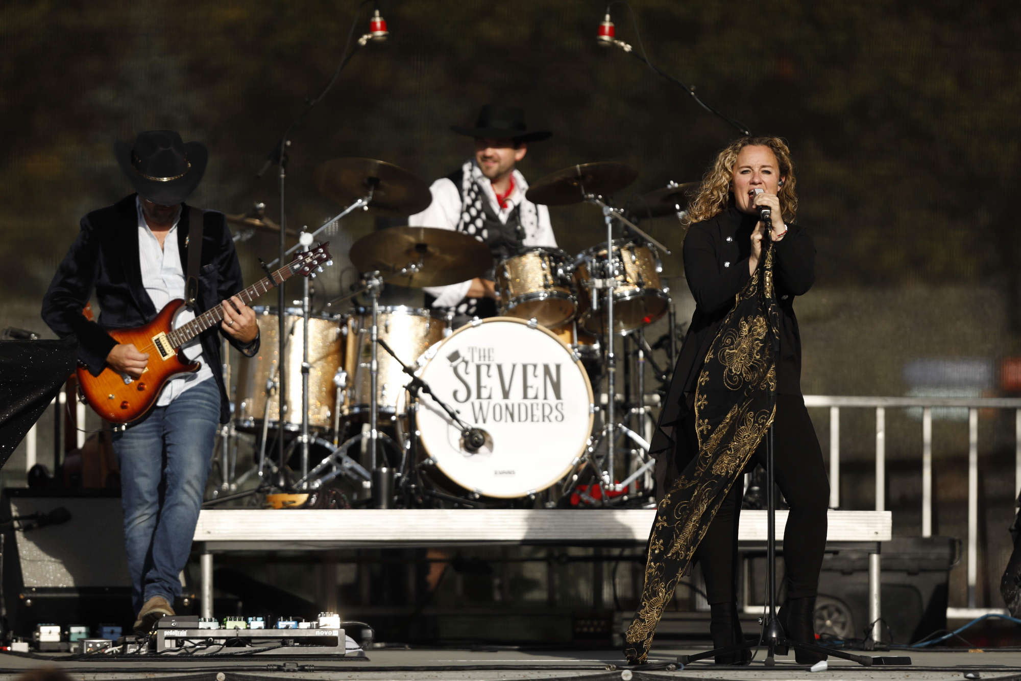 The lead singer, guitarist, and drummer from the Seven Wonders perform on stage during Meliora Weekend 2023.