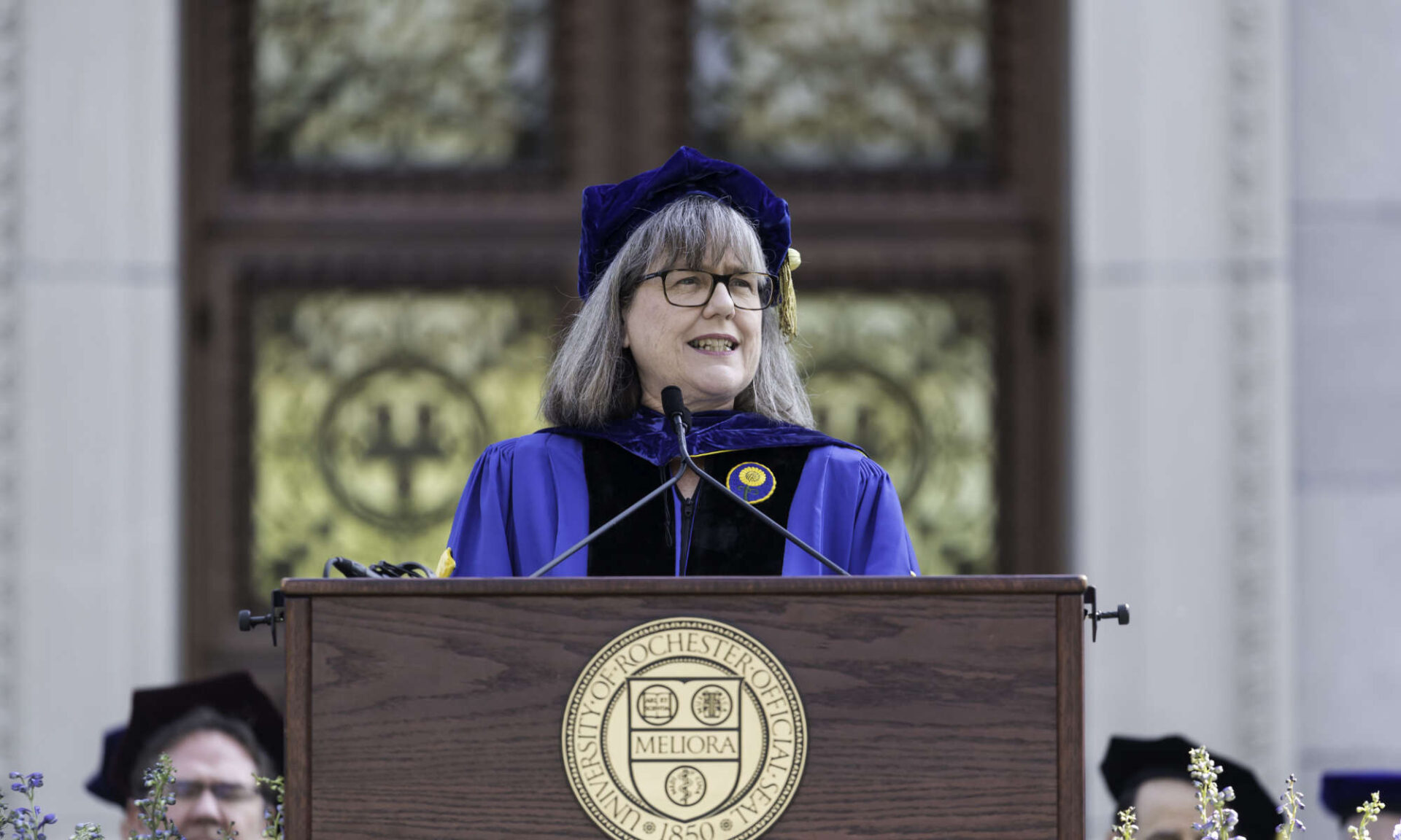 Donna Strickland in University of Rochester regalia speaking at a podium during commencement.