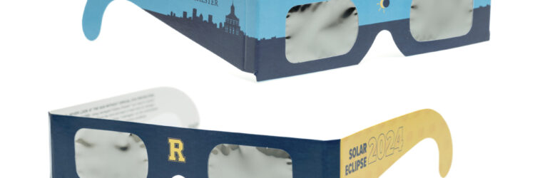 Two pairs of University of Rochester-branded solar eclipse glasses against a white background.