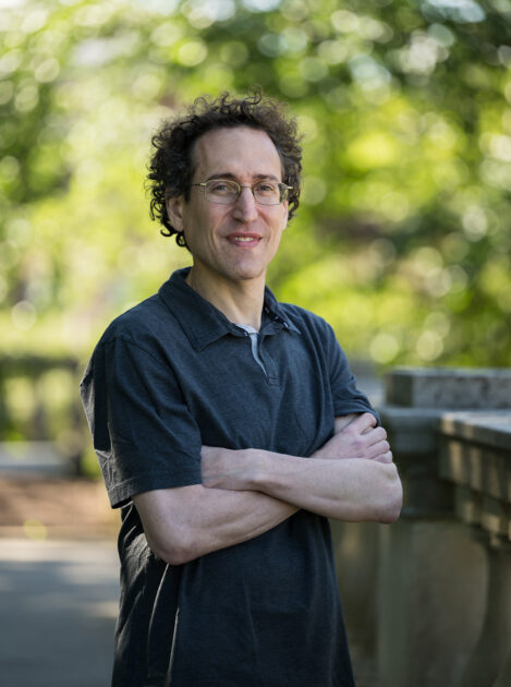 Portrait of Druckman standing outdoors with trees in background.