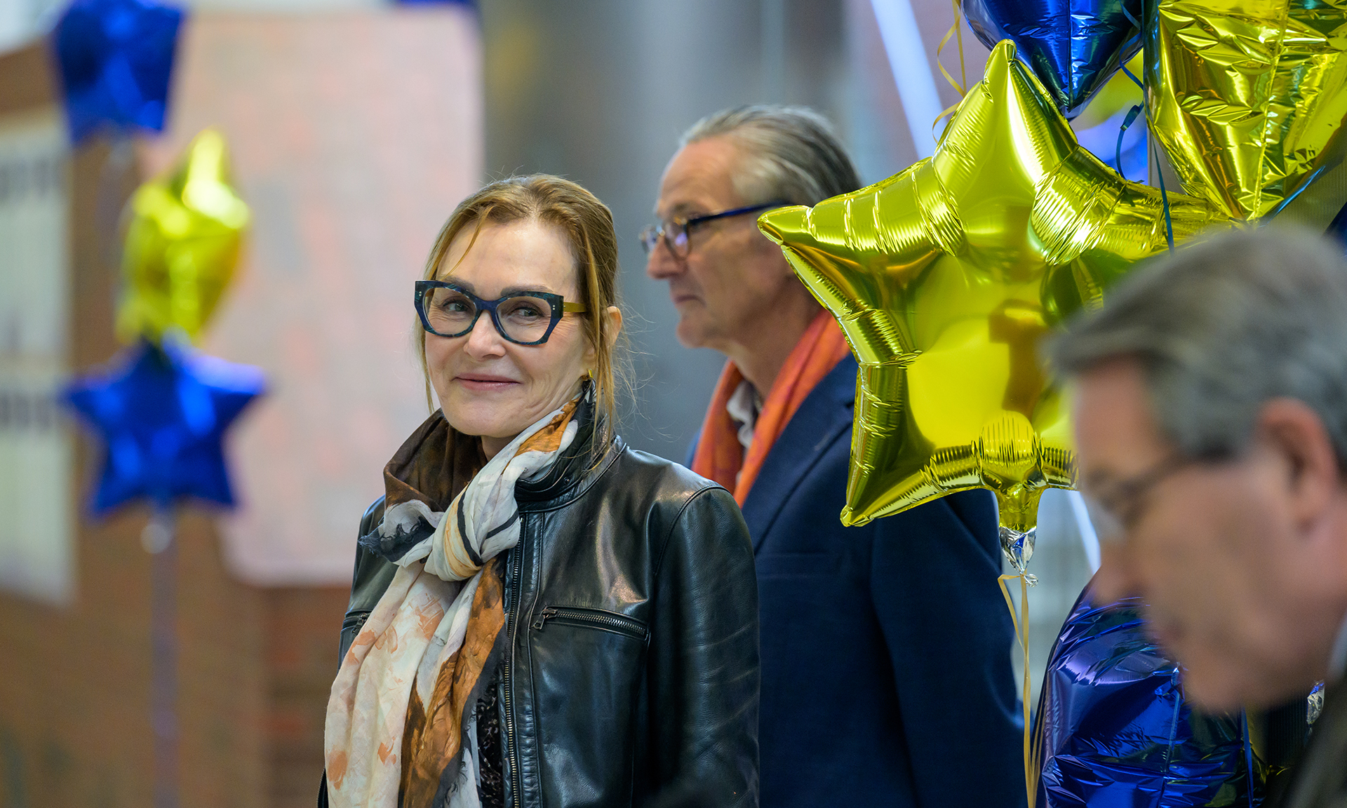 Feature image Lynne Maquat, surrounded by colleagues and balloons, smiles and looks to the side during a press conference.