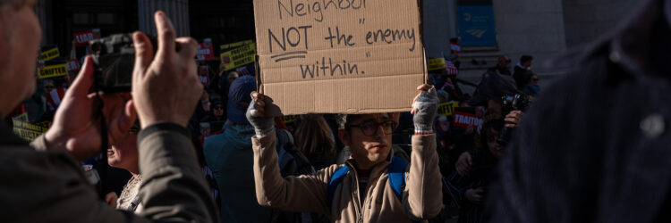 protester at a rally holds up a sign that reads I'm your neighbor BOT the enemy within.