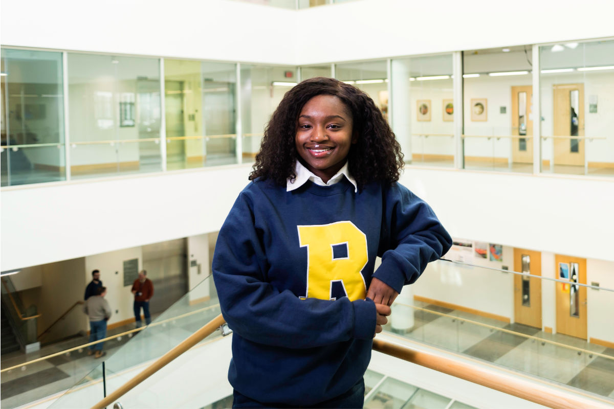 Kharimat Alatise smiles at the camera sporting a University of Rochester "spirit R" sweatshirt.