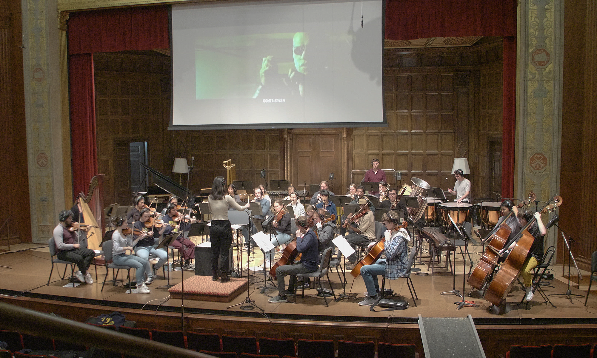 student musicians play on a stage with a film projected behind them to illustrate a film score analysis class at the Eastman School of Music.