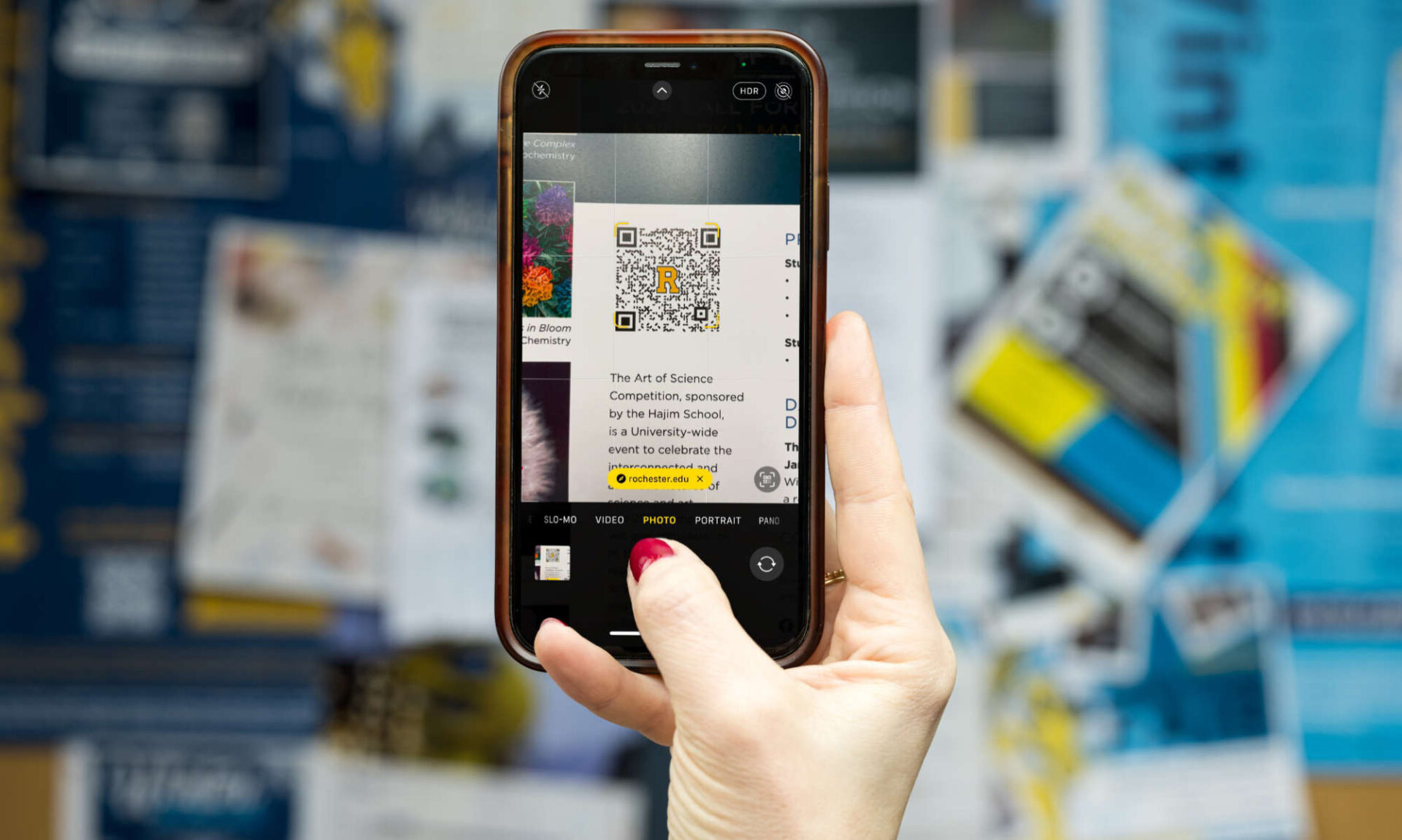 A hand holds up a phone and on the screen the new QR code technology to prevent quishing.