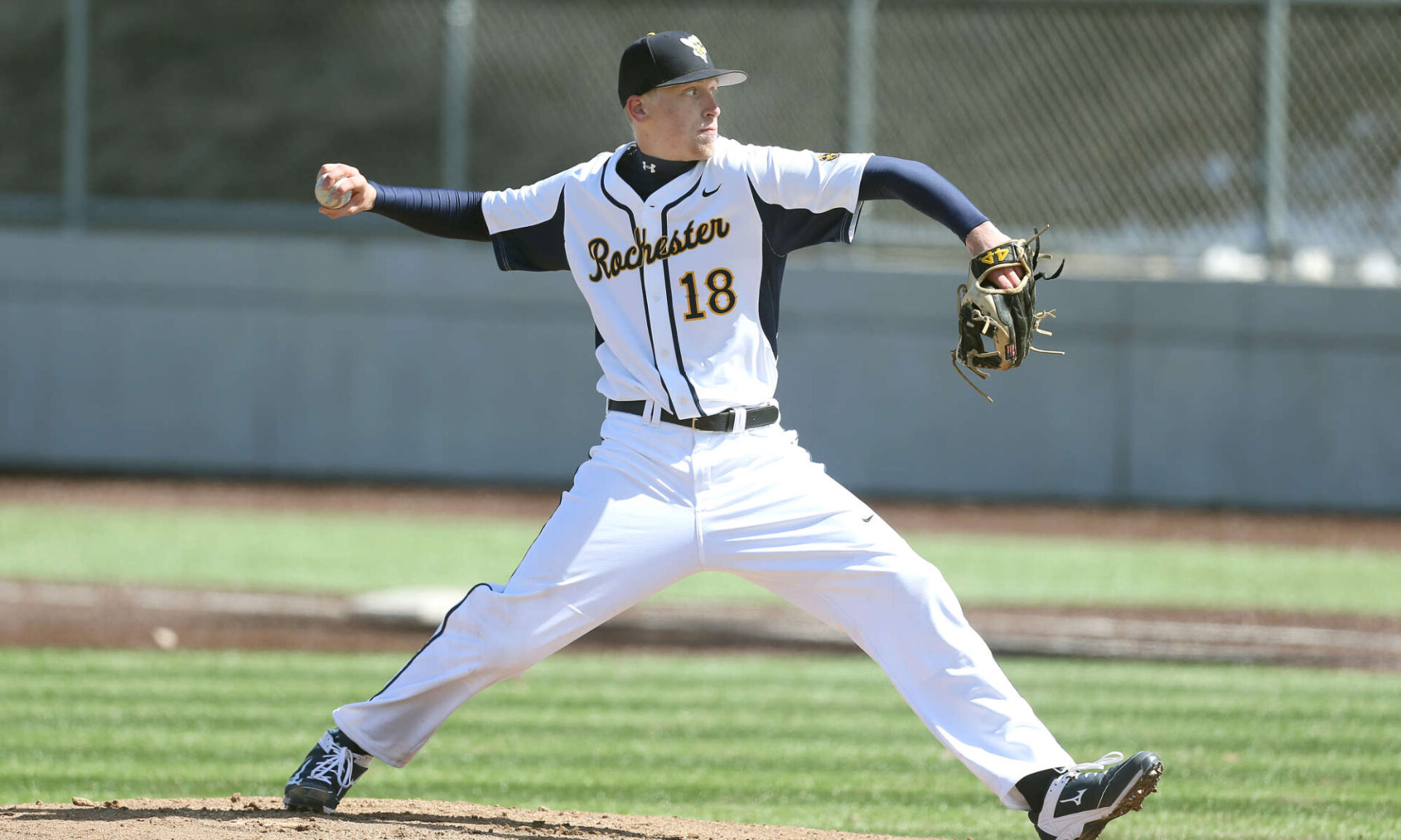 John Ghyzel in a University of Rochester Yellowjackets uniform pitching a baseball.