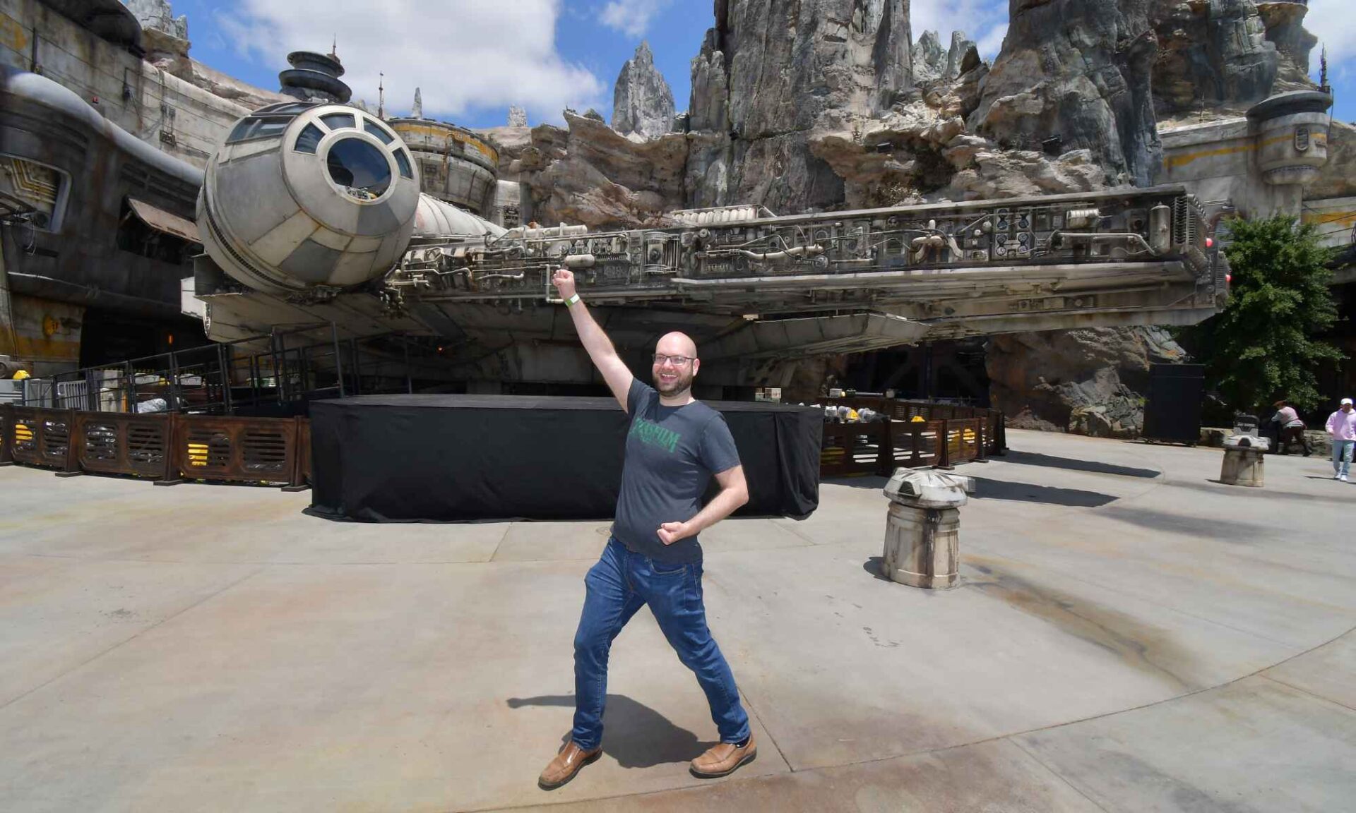 Steve Blank poses triumphantly with one arm raised in the air in front a replica of the Millennium Falcon.
