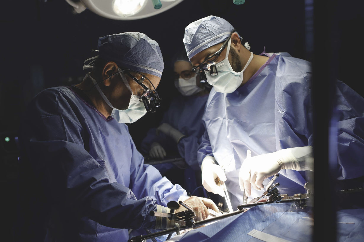 Two University of Rochester Medical Center professionals in medical gear and masks perform surgery.