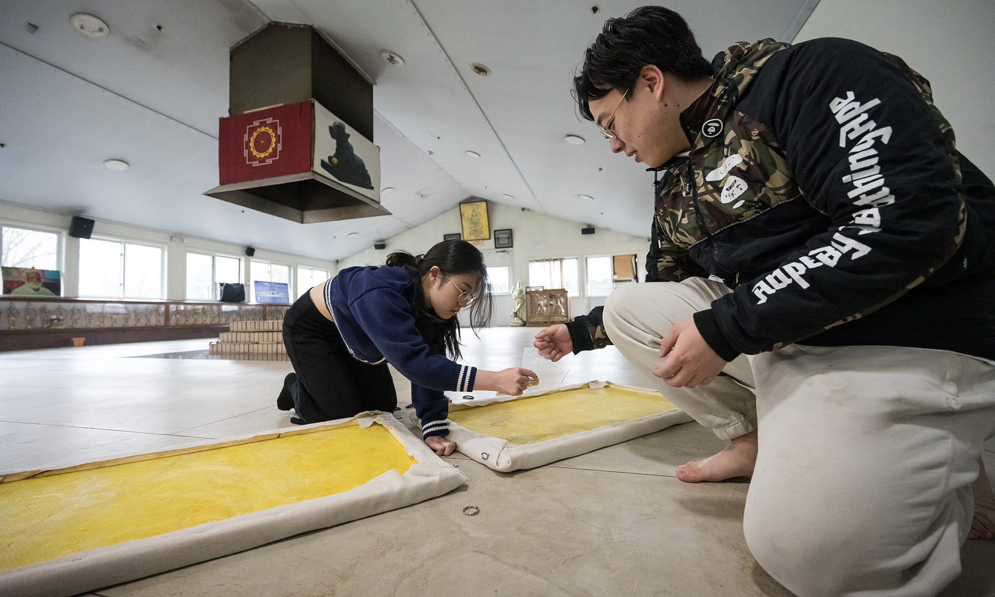 two students make adjustments to two yellow panels on the ground.