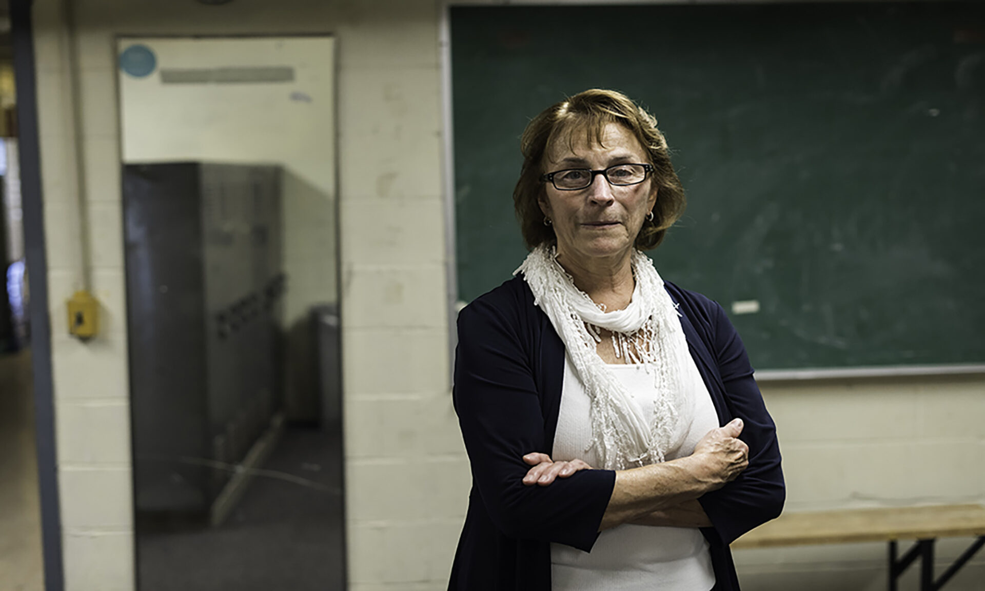 Jane Possee stands with her arms crossed in a locker room.