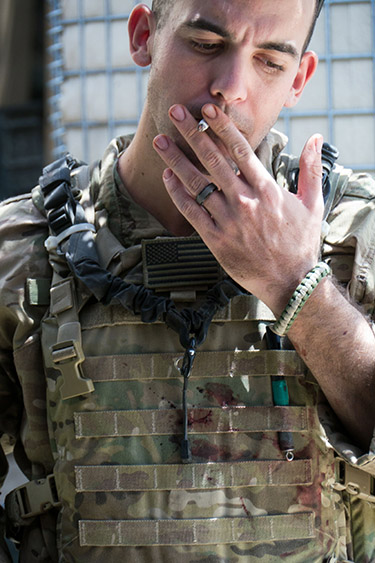Close up of a US army soldier in uniform taking a drag on a cigarette.