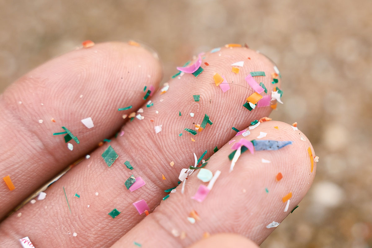 A finger covered in colorful confetti, highlighting the presence of microplastic in the environment.