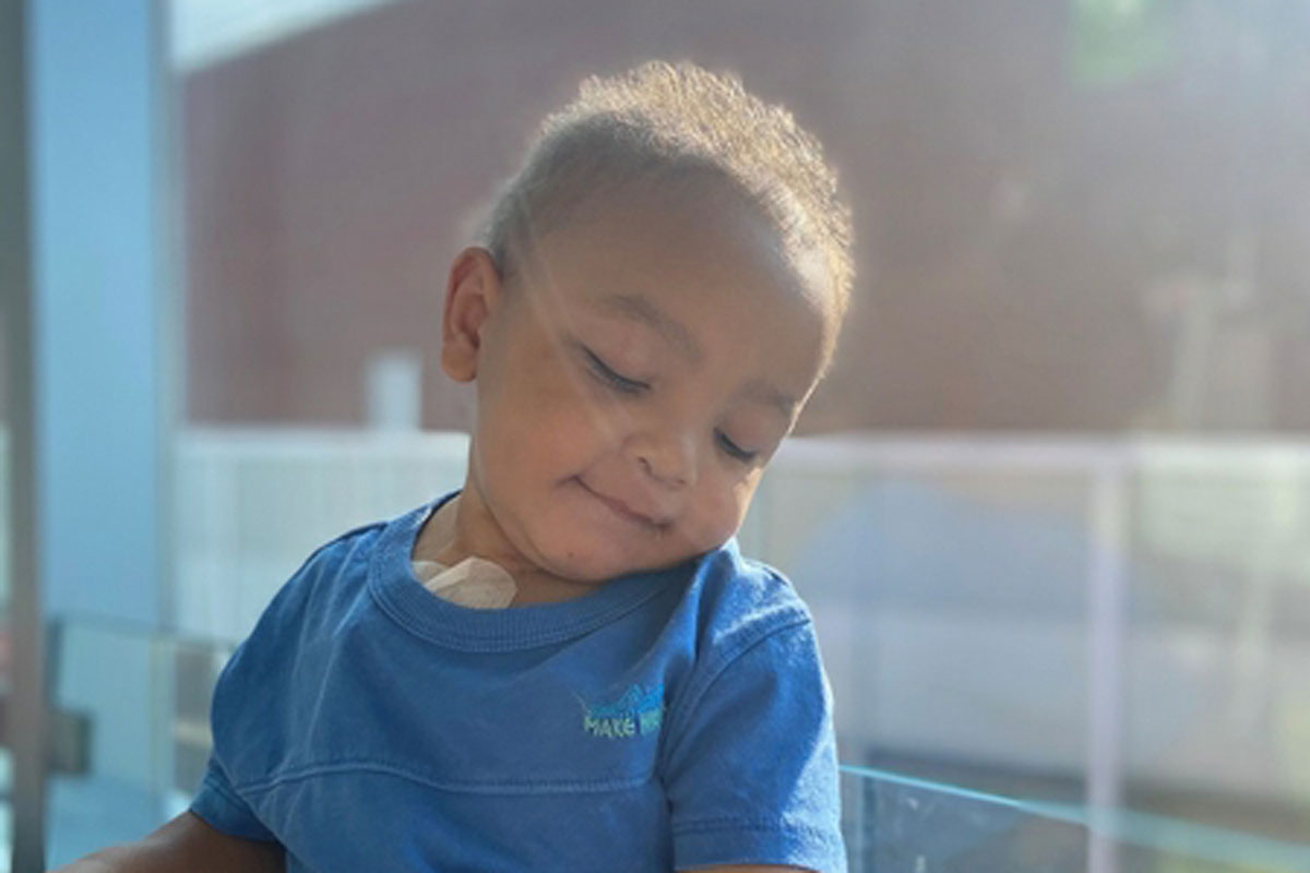 Young boy in a blue shirt sitting on a table at the University of Rochester Medical Center, named Noah Ludgood.