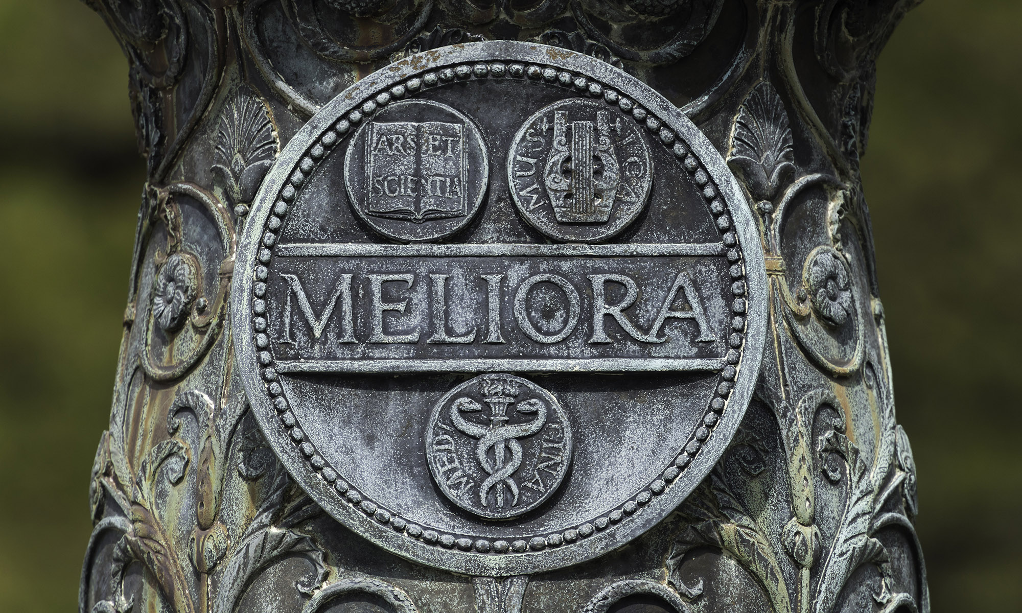 Weathered Meliora engraving on base of a flagpole.