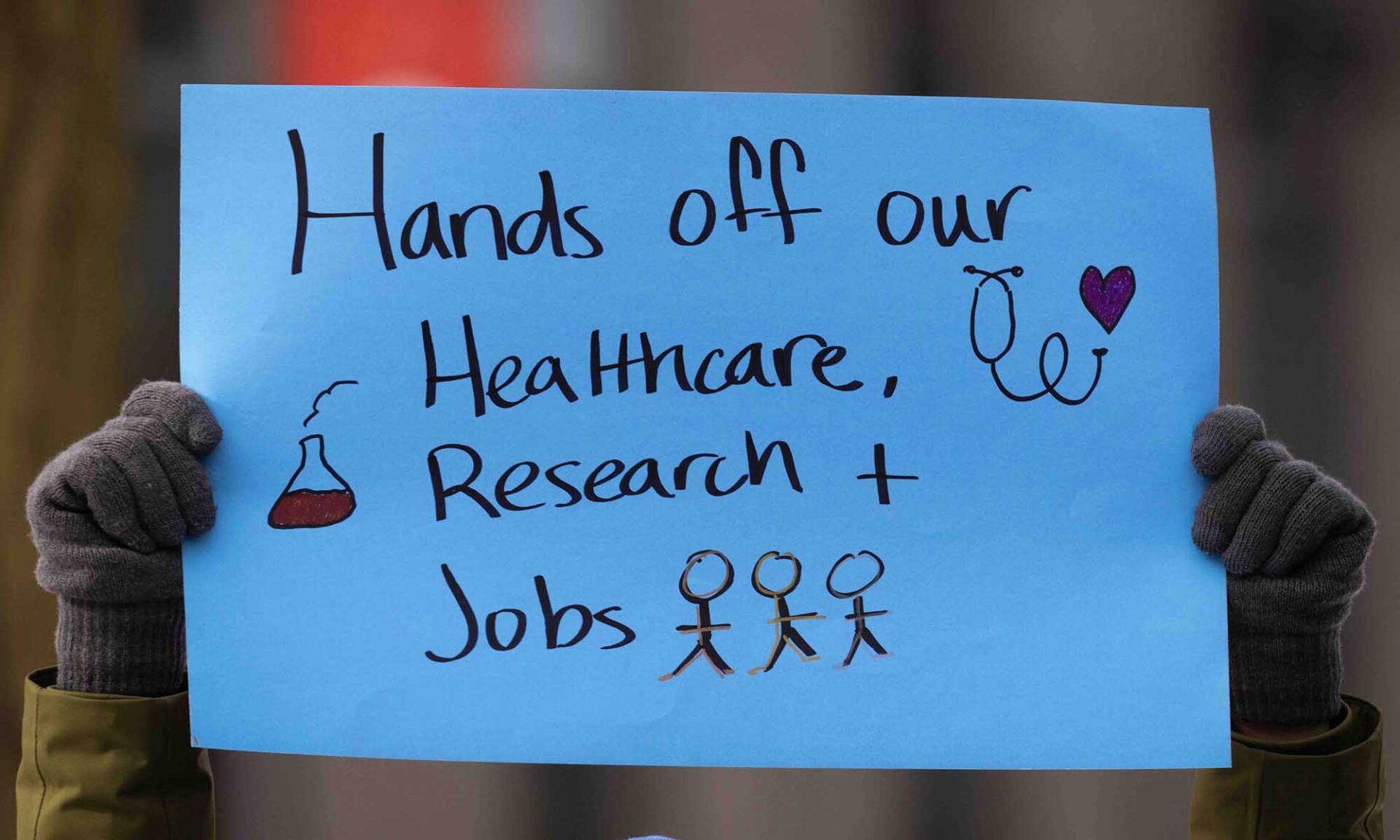 Two hands hold up a blue poster that says 