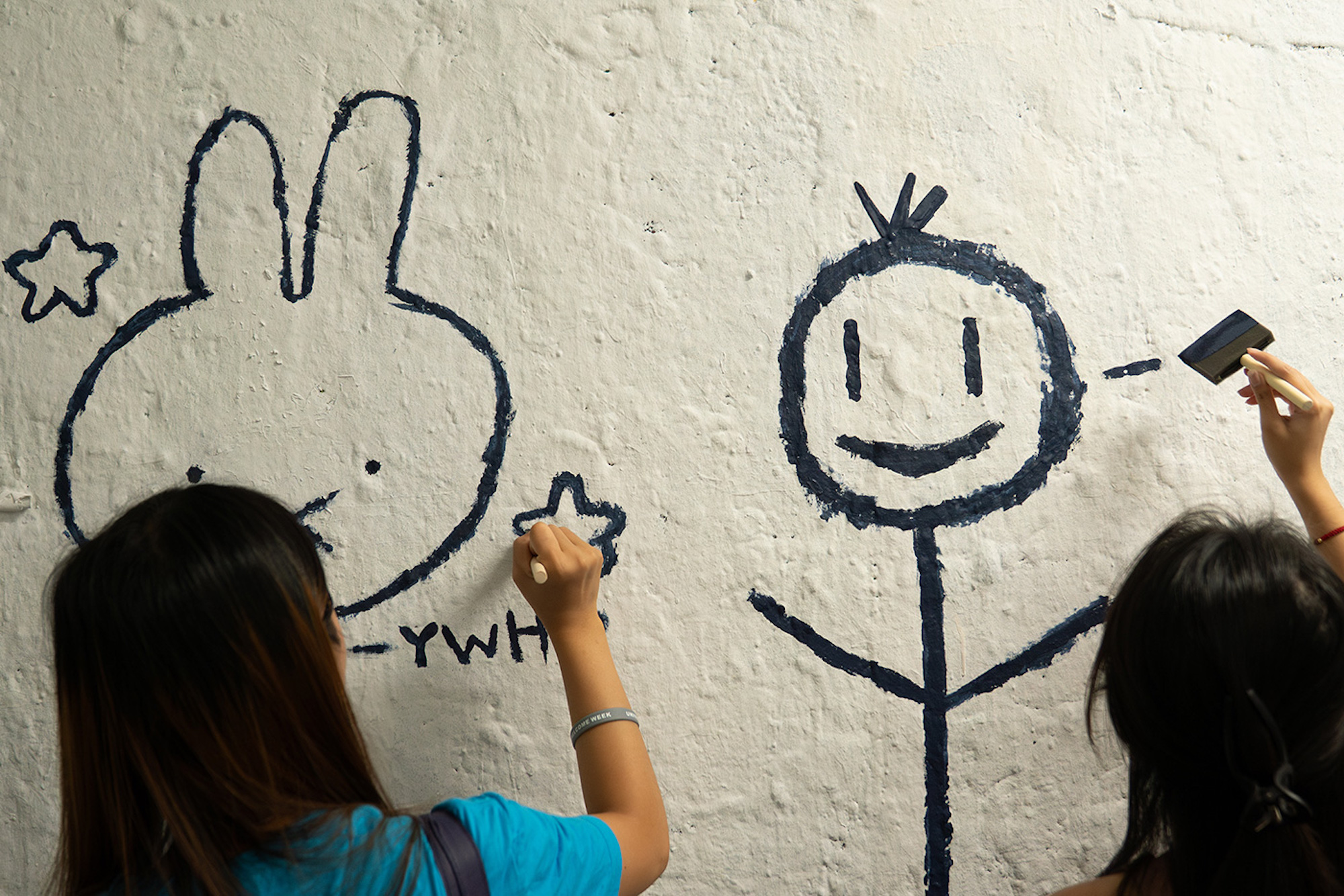 Students paint cartoons and stick figures on tunnel walls. 