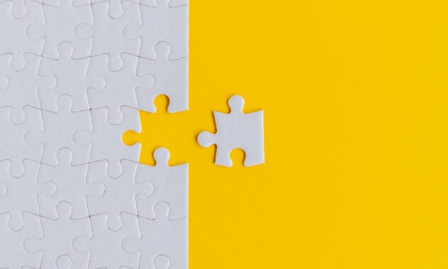 Image of a white puzzle against a yellow background with a final white piece just away from completing the puzzle.