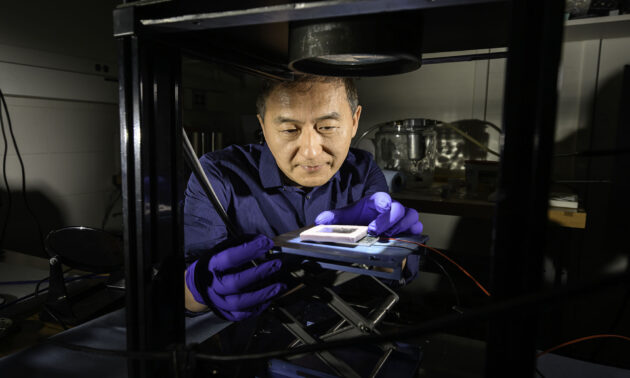 Chunlei Guo hovering over a simulator to test sunlight absorption of a solar thermoelectric generator device he holds.