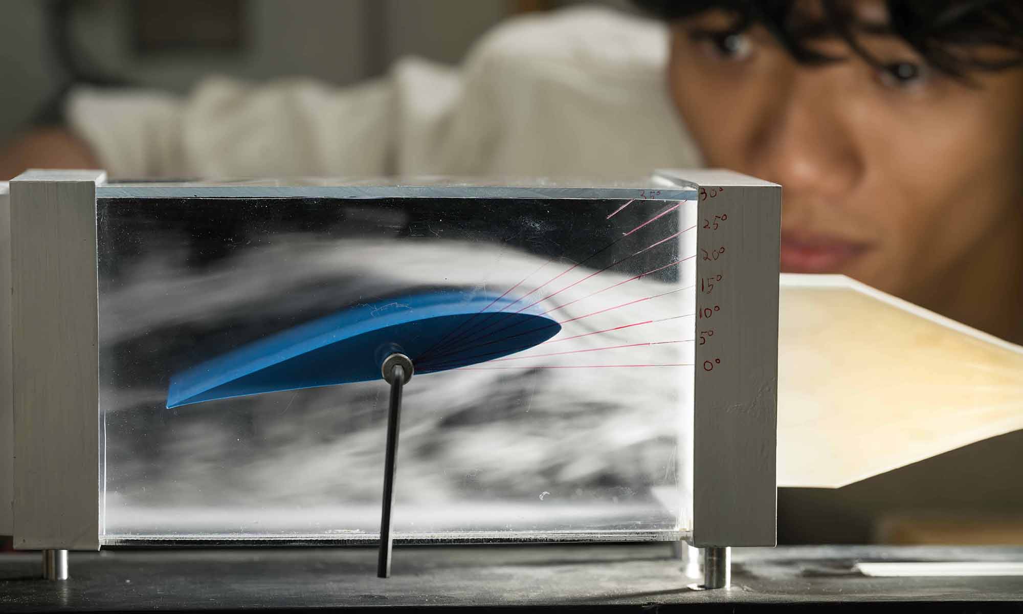 Close-up of a student watching as machine smoke flows over an adjustable 3D-printed wing.