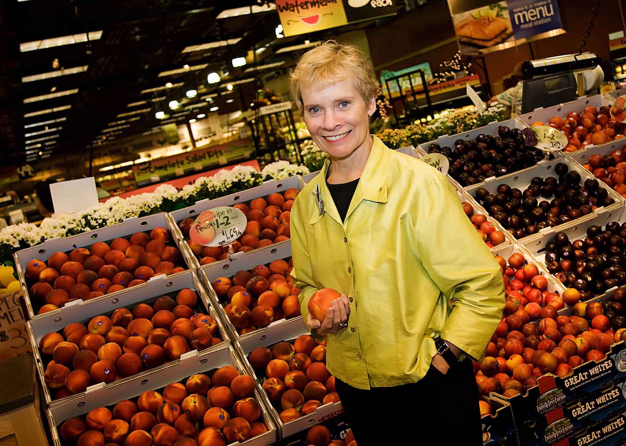 Mary Ellen Burris holds a peach in the produce section of Wegmans.