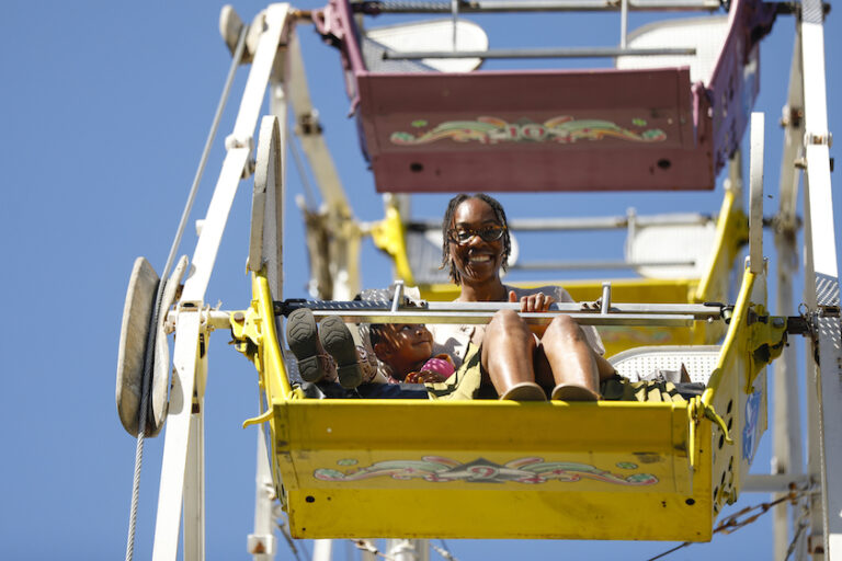 A mother and child wave from atop a Ferris wheel.