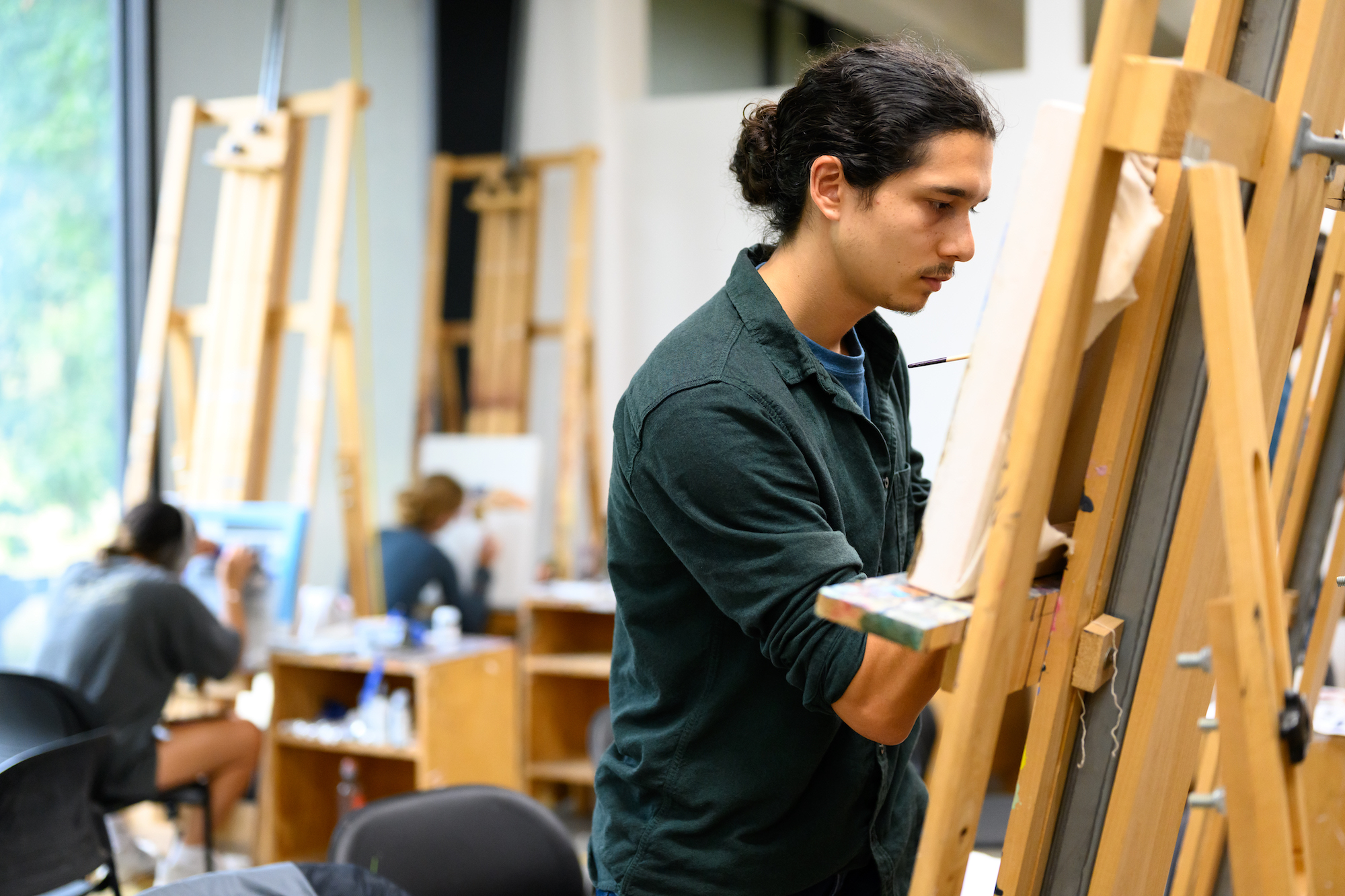 Students painting at an easel during an advanced painting class. 