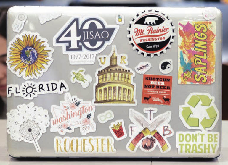Close up of a laptop covered in University of Rochester stickers.