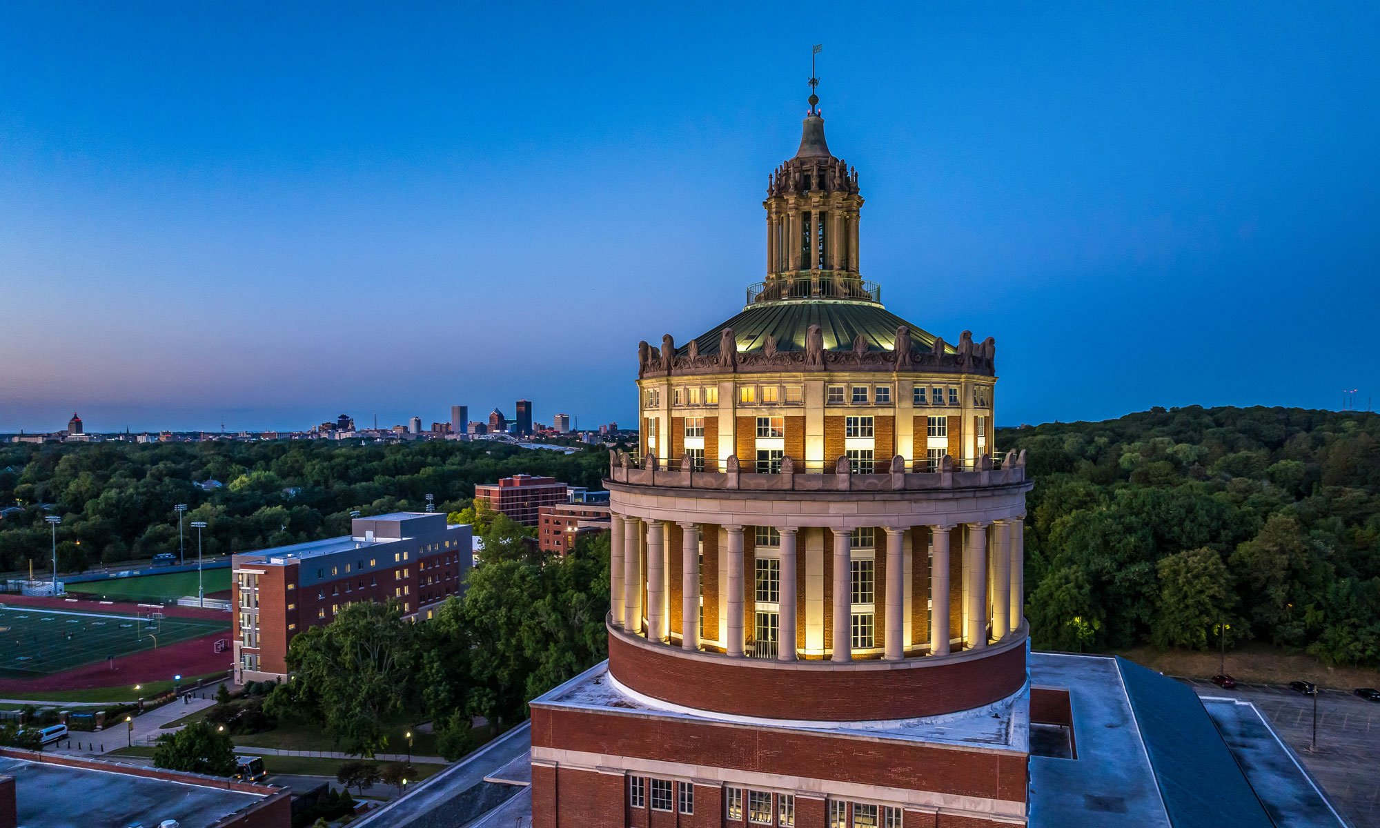 Rush Rhees Library and the Meliora sign illuminated at night.