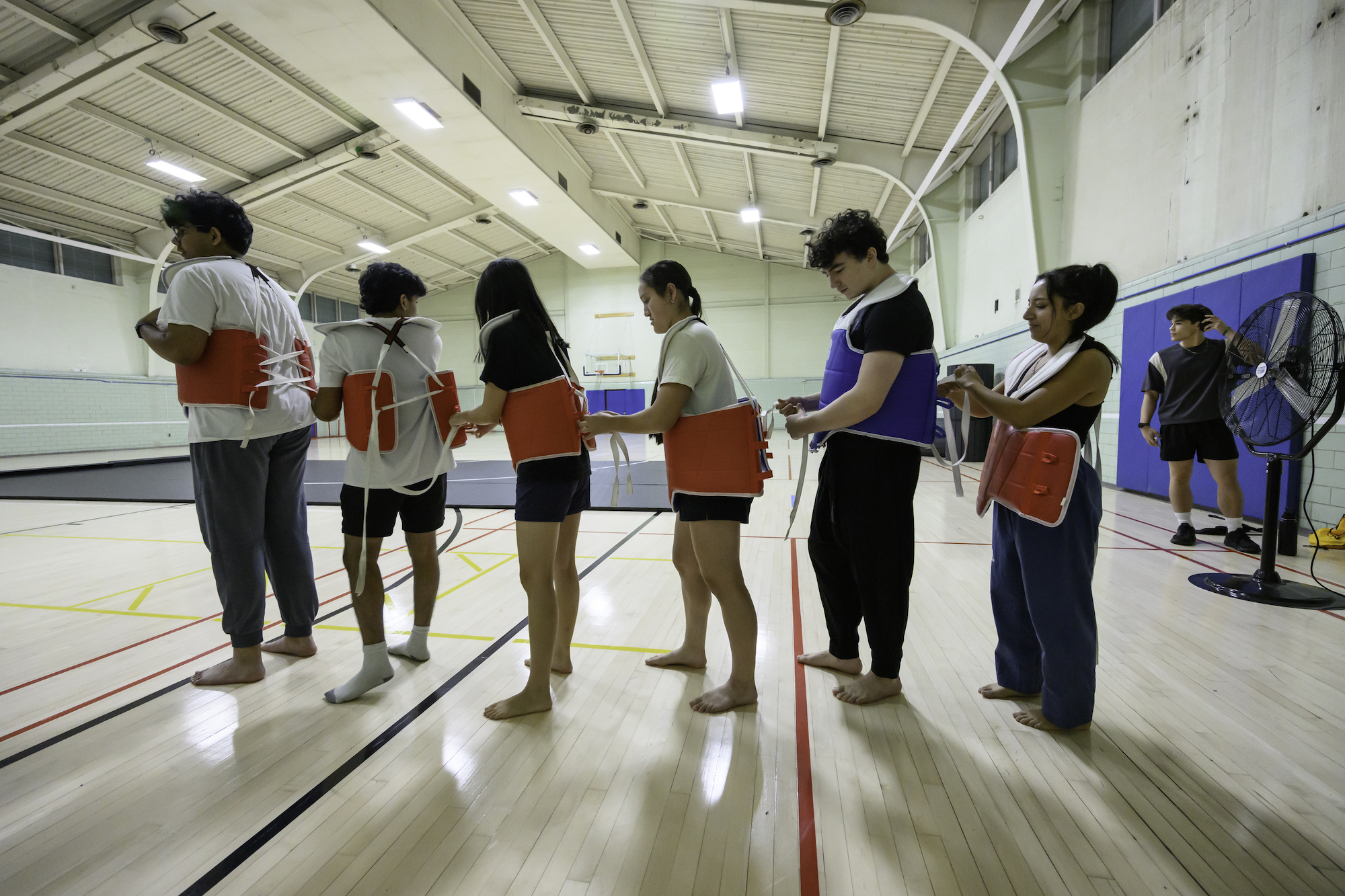 Members of the UR taekwondo club affix protective gear to one another.