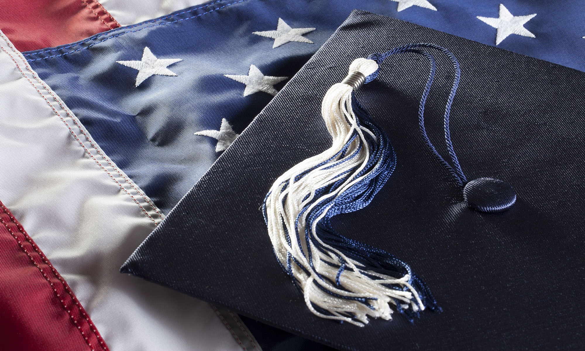 Black graduation cap on top of an American flag.