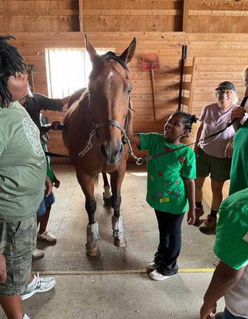 Local children smiling and petting a therapy horse. 