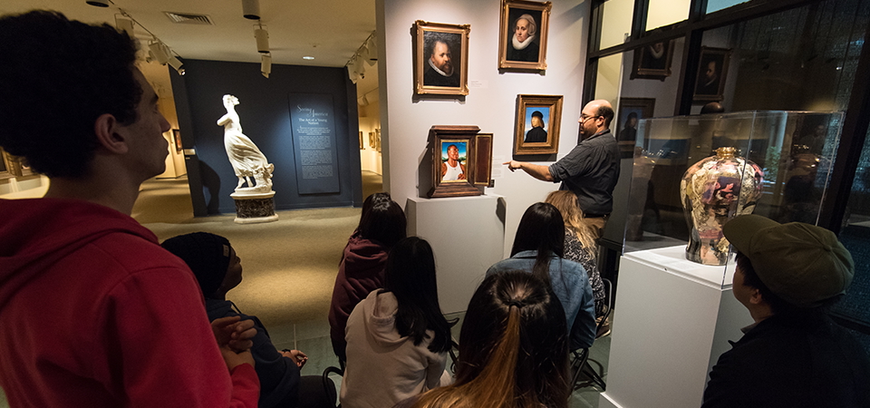 A group of people at the Memorial Art Gallery watch as a docent explains art in the collection.