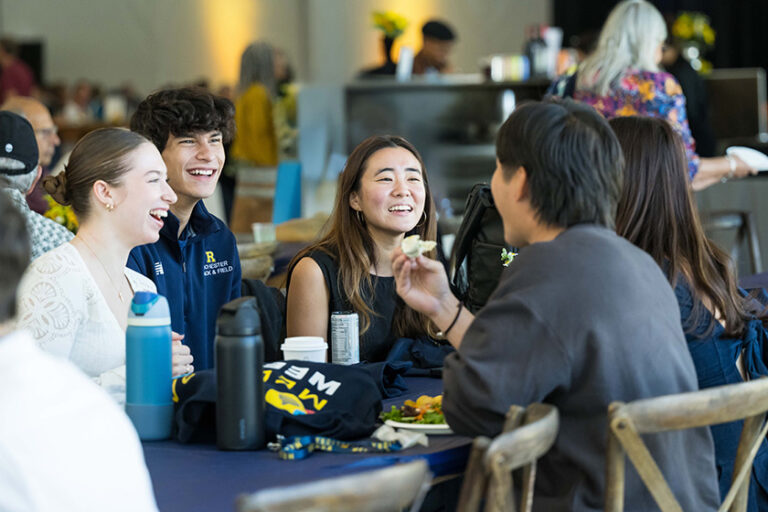 Group of URochester young alumni at a table during Meliora Weekend.