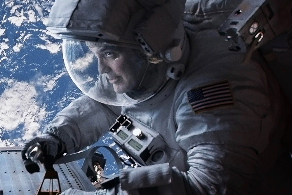 An astronaut floating in space holds a bottle of water, surrounded by stars and the Earth in the background.
