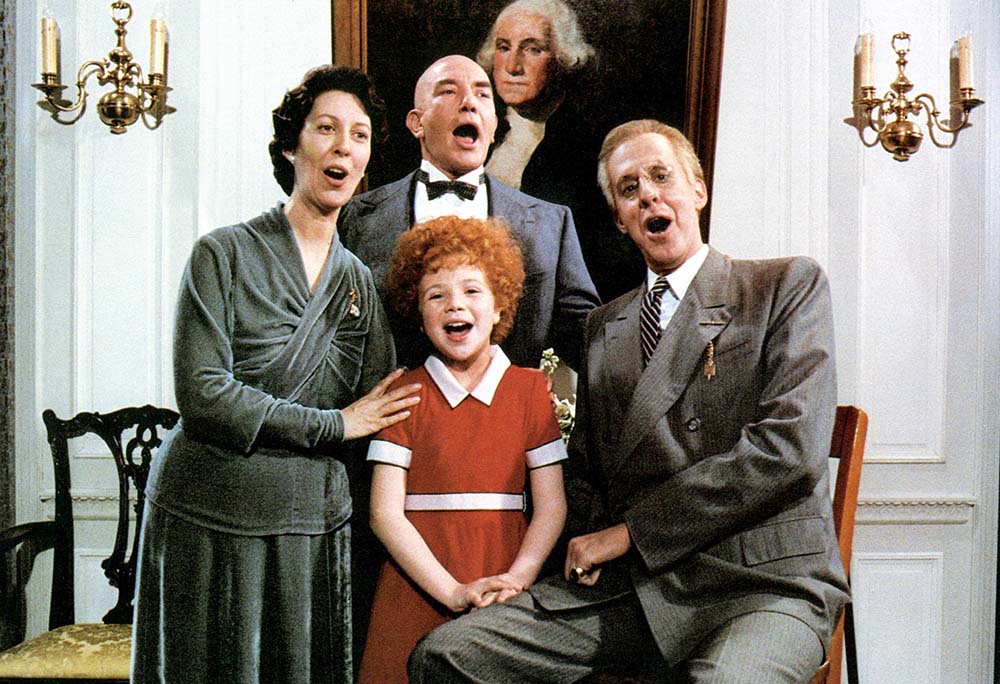 A family smiles together for a photo in front of a colorful painting in a gallery setting.