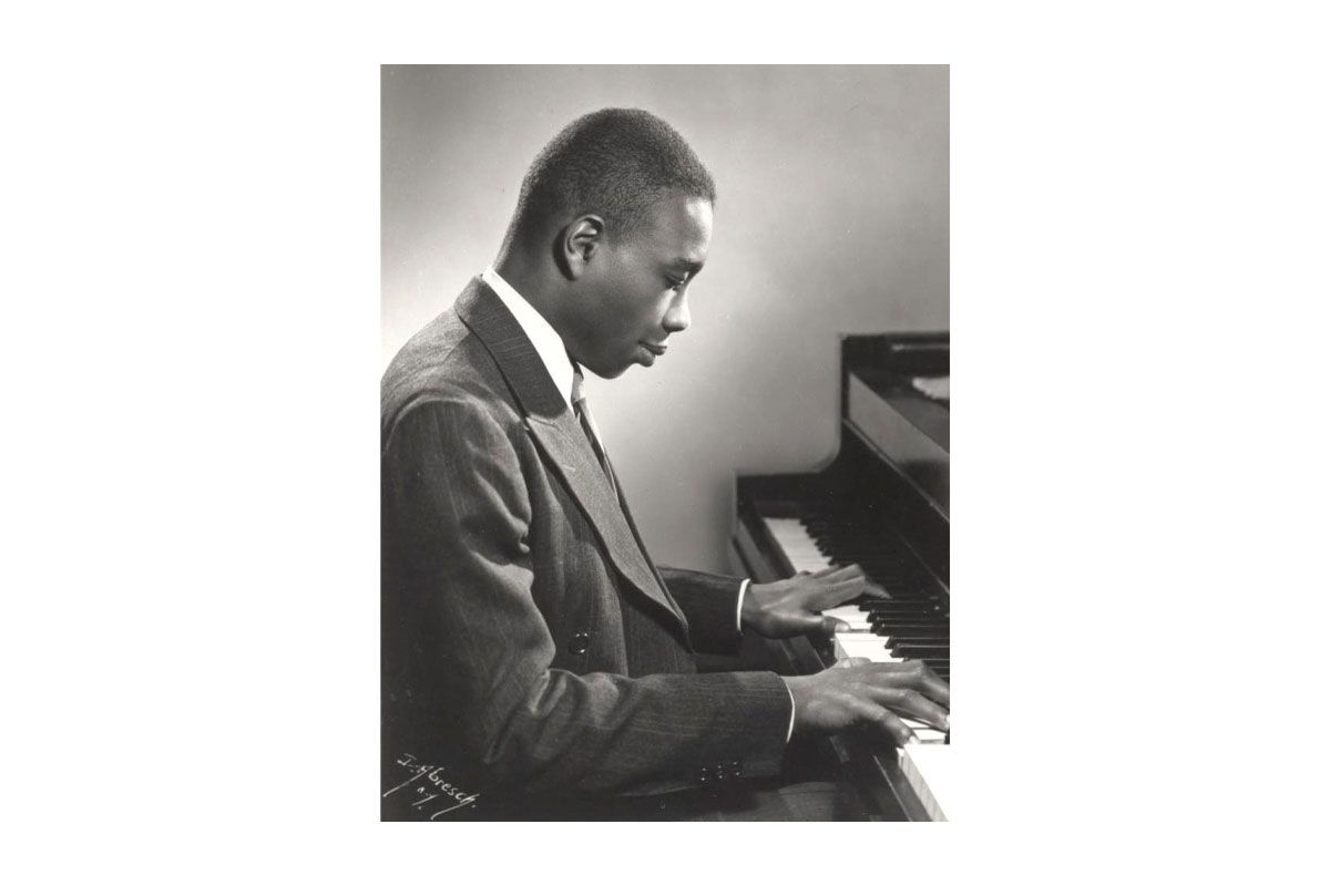 Black and white photo of Pulitzer Prize winner George Walker, the first African American Eastman doctorate holder, playing piano.