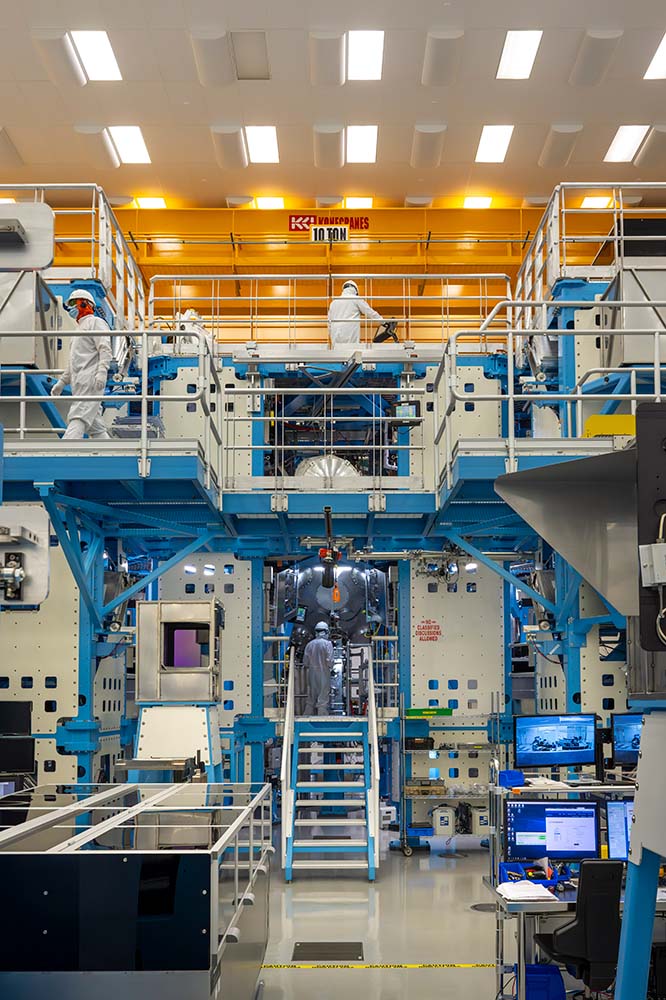 A large room filled with people collaborating on projects involving lasers and technology.