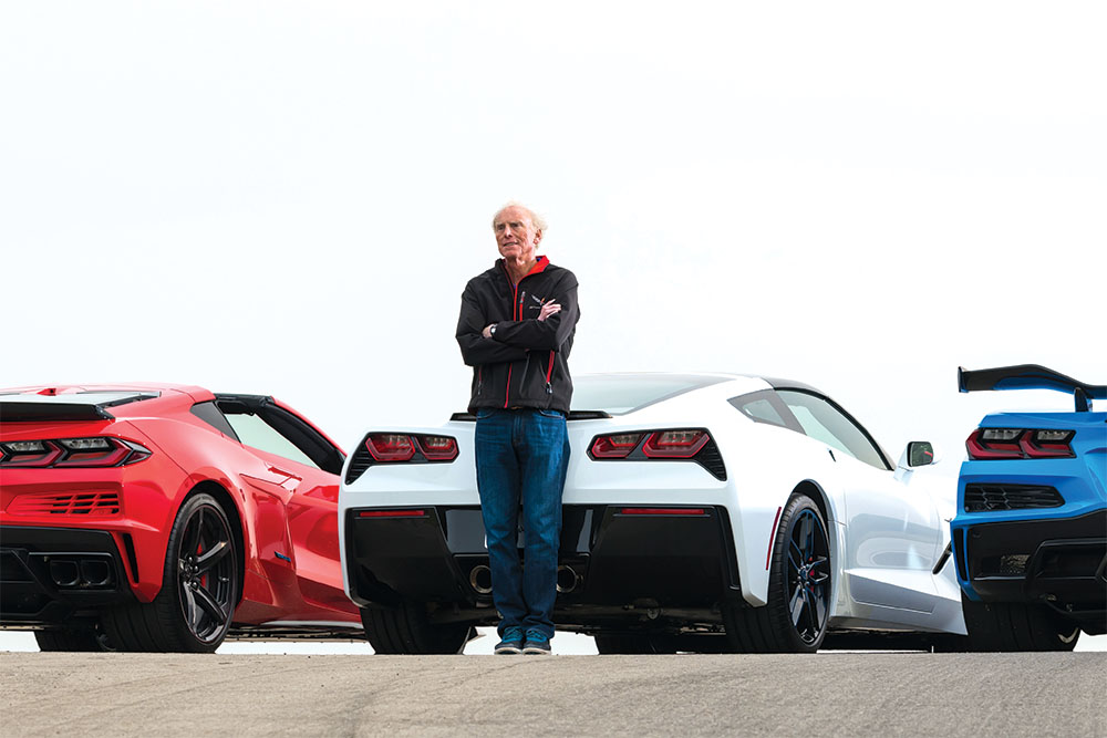 A man stands beside three colorful Corvettes parked in a row, showcasing their sleek designs and vibrant paint jobs.