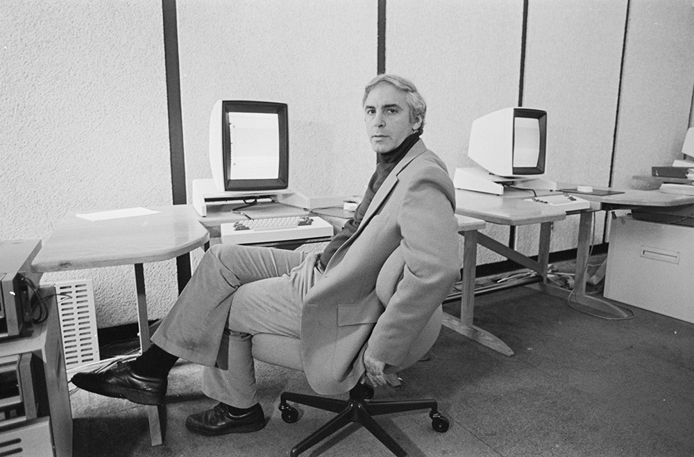 A man seated at a computer desk, focused on the screen in front of him.