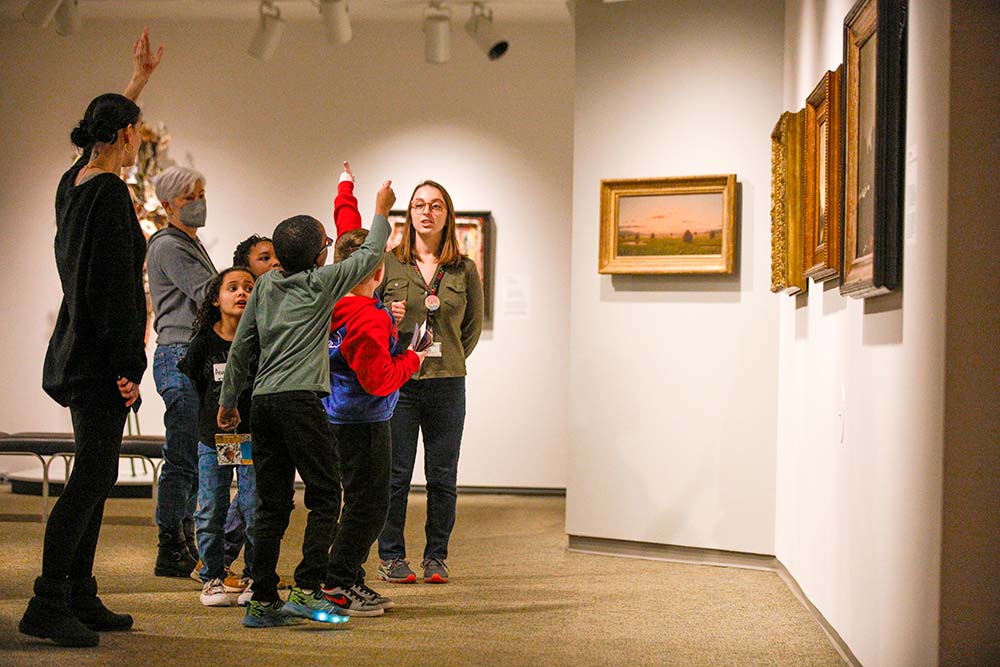 Visitors admiring paintings in an art museum, showcasing a variety of artistic styles and expressions.
