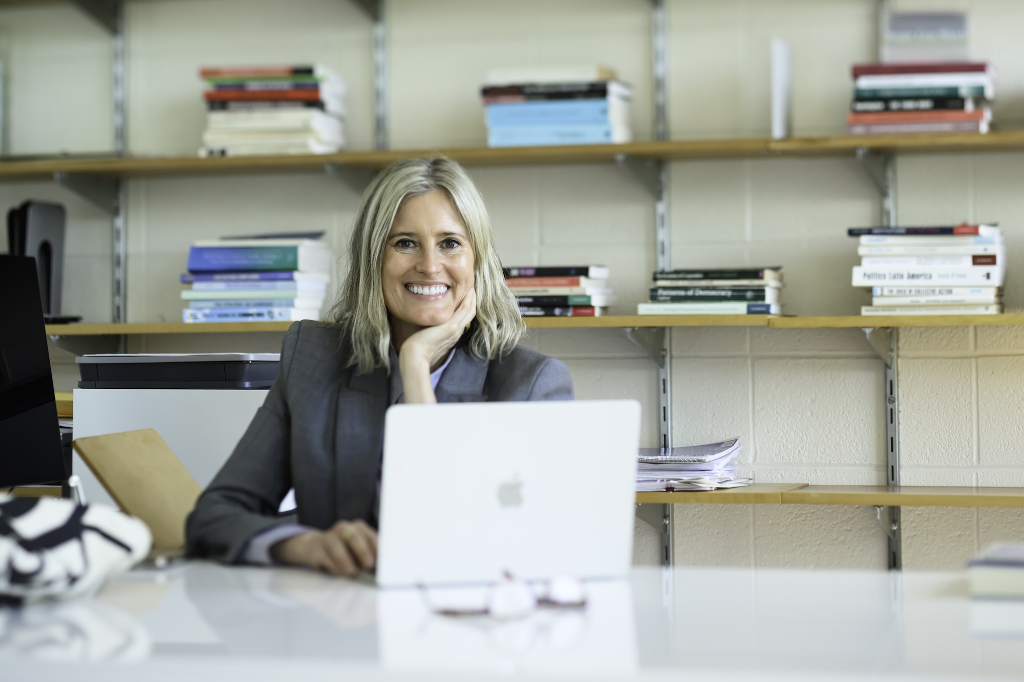 Poltical science professor Gretchen Helmke at her desk with her laptop and bookshelves behind her.
